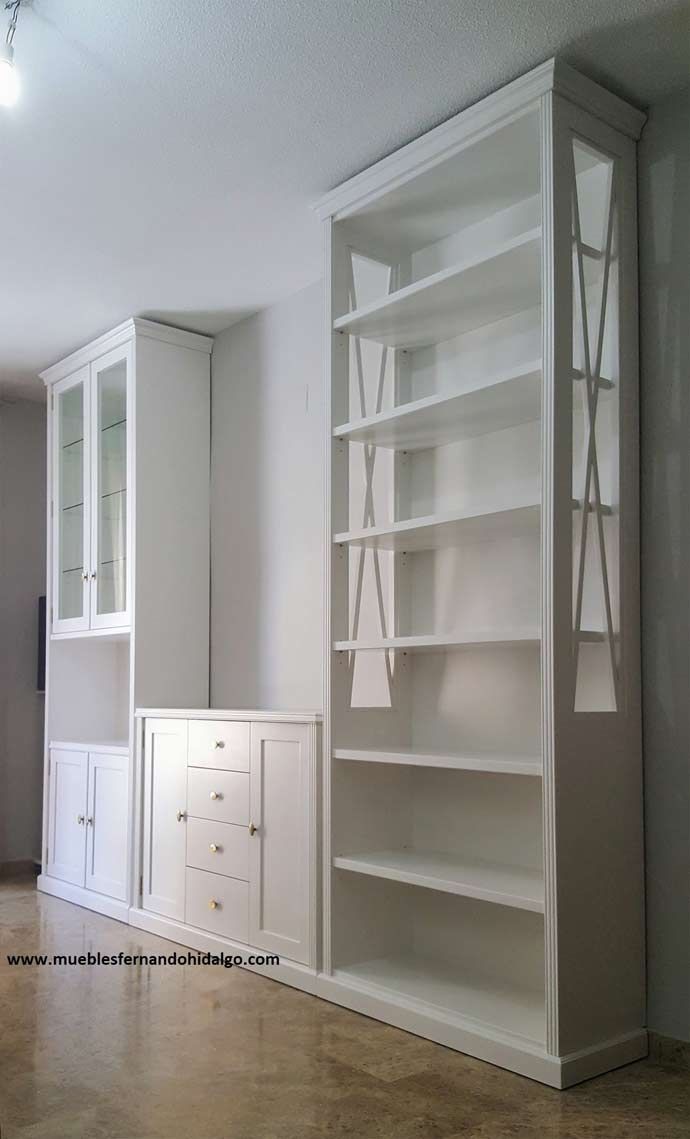 Una sala de estar con estantes y armarios blancos.