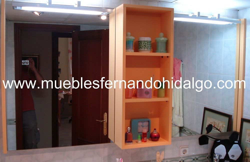 Un baño con espejo y estanterias y la pagina web www.mueblesfernandohidalgo.com