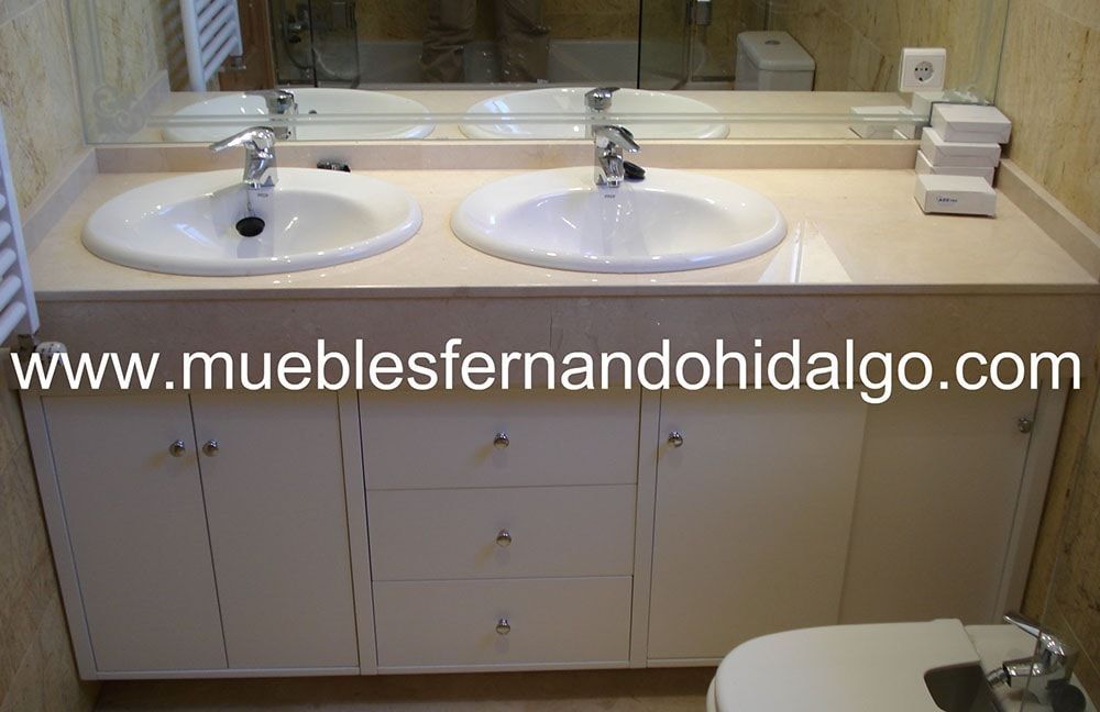 Un baño con dos lavabos y un inodoro y la página web www.mueblesfernandohidalgo.com
