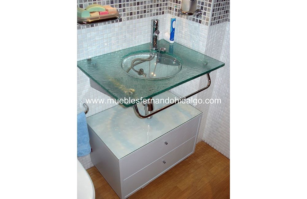 Un lavabo de baño con tapa de cristal y grifo.