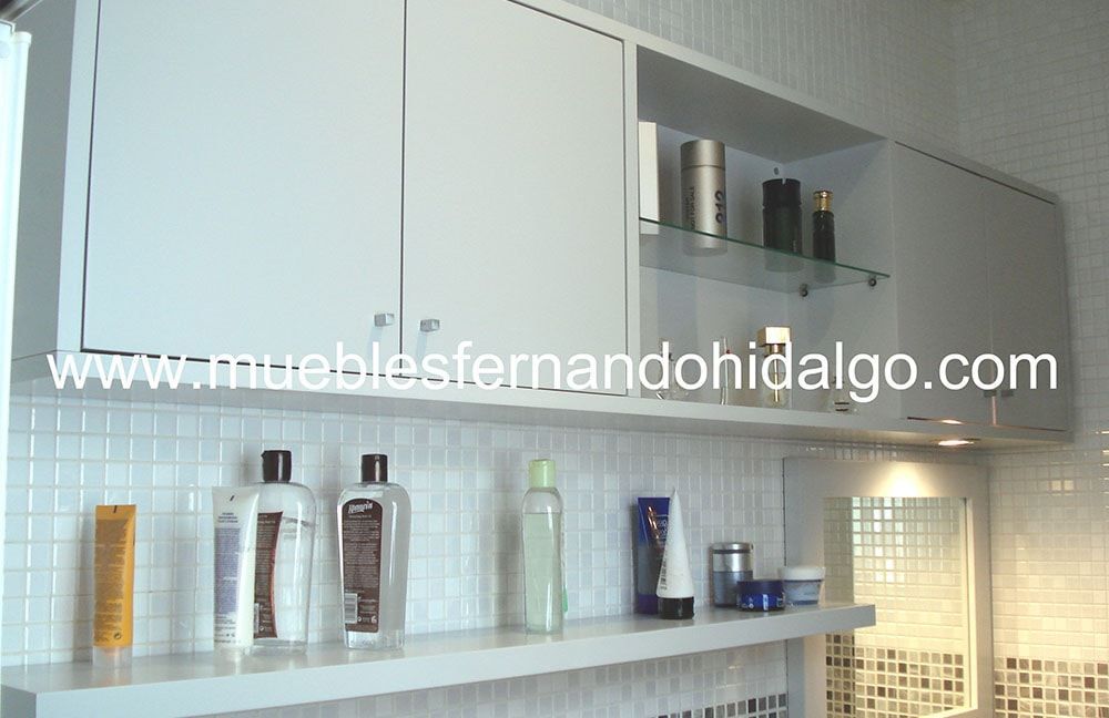 Un baño con muebles y estantes blancos y la página web www.mueblesfernandohidalgo.com
