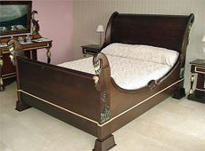 Una cama trineo de madera con un edredón blanco en un dormitorio.