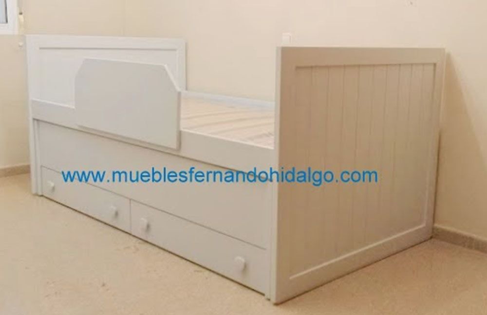 Una cama blanca con cajones debajo está en una habitación.