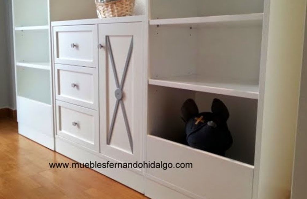 Un perro está sentado en la esquina de un armario blanco.