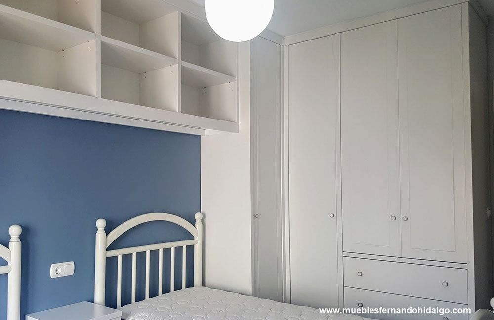 Un dormitorio con cama, mesita de noche, armario y estanterías.