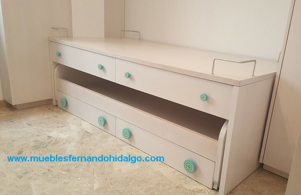 En una habitación hay una litera blanca con tiradores azules.