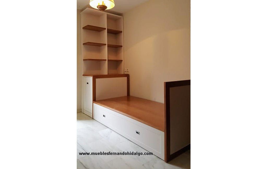 Un dormitorio con una cama, estanterías y una lámpara.