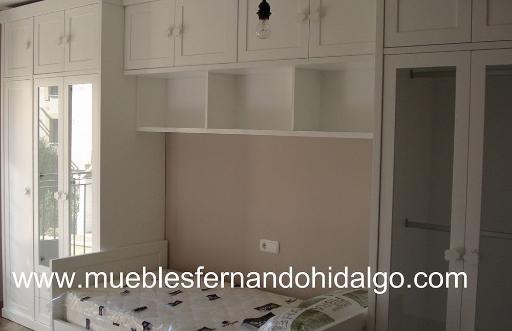 Un dormitorio con cama y armario con la web www.mueblesfernandohidalgo.com en la esquina