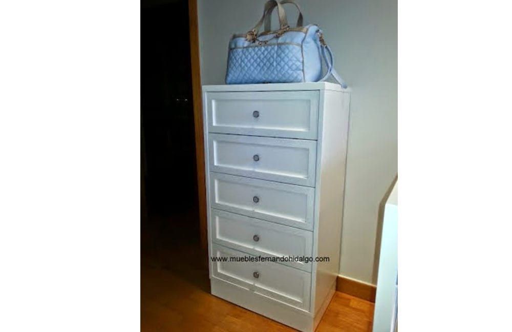 Una cómoda blanca con una bolsa azul encima.