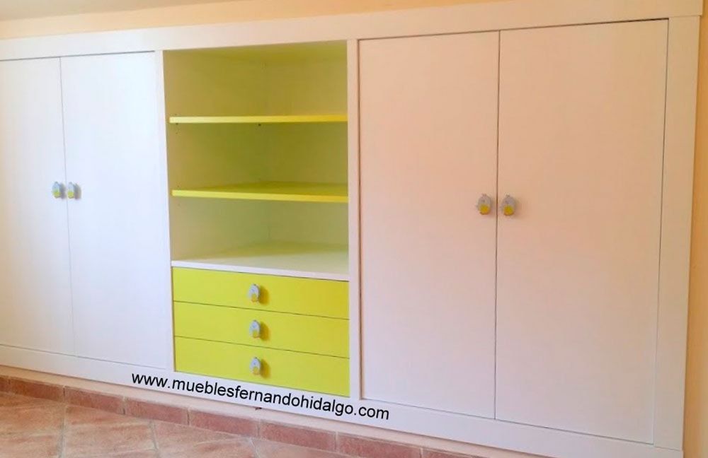 Un mueble blanco con cajones y estantes amarillos tiene en la parte inferior el sitio web www.mueblesafernandodiego.com