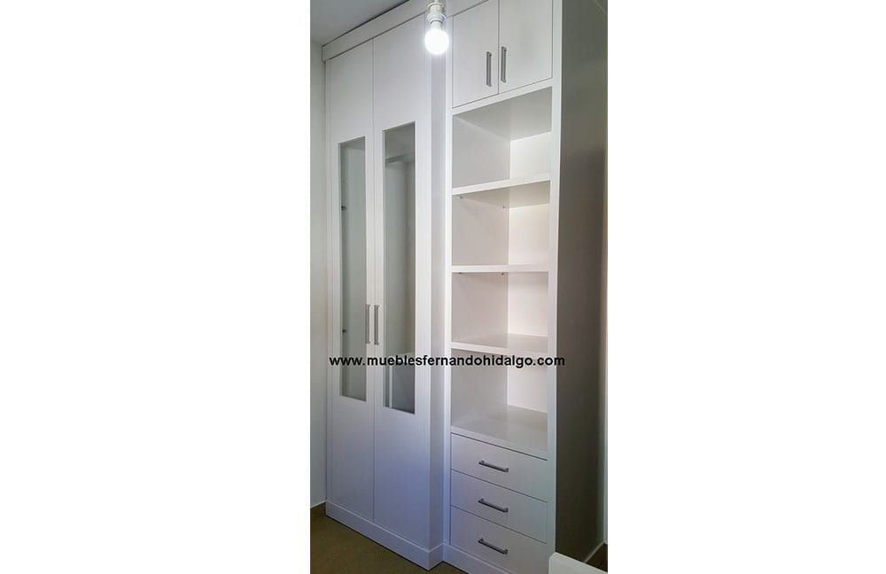 Un armario blanco con estantes y cajones en una habitación.