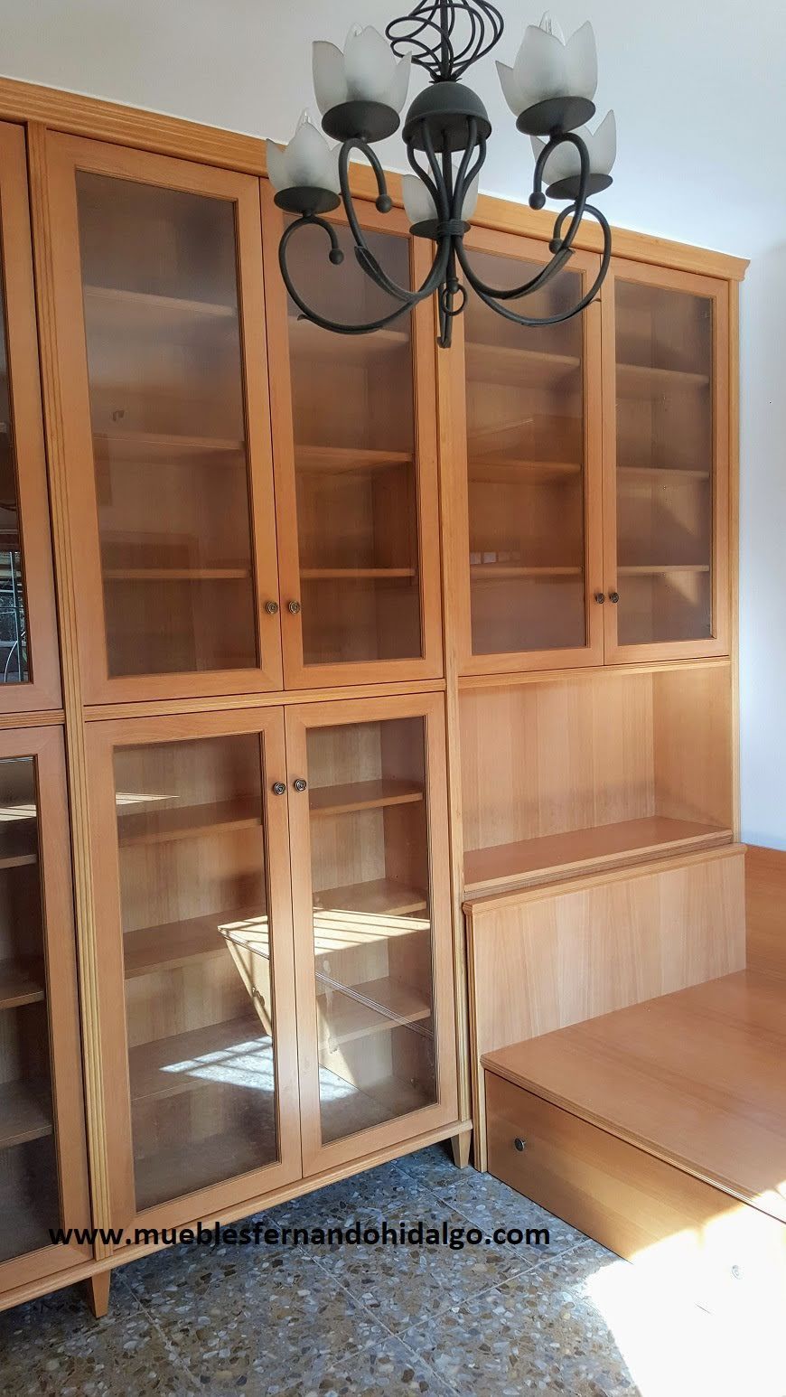 Un armario de madera con puertas de cristal y una lámpara de araña en una habitación.