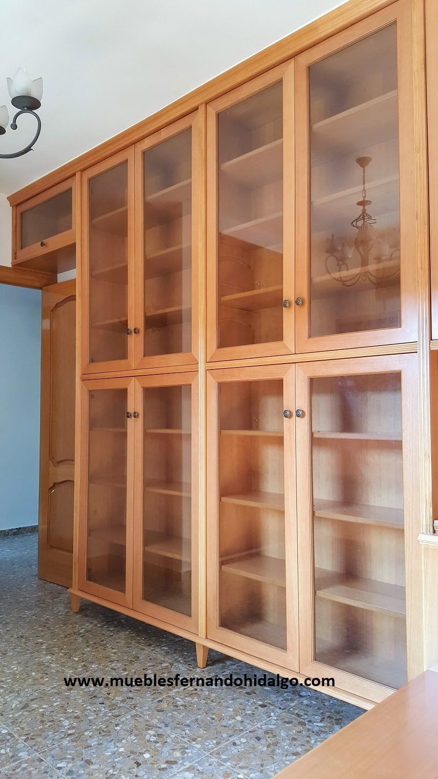 Una habitación con muchos estantes y puertas de cristal.