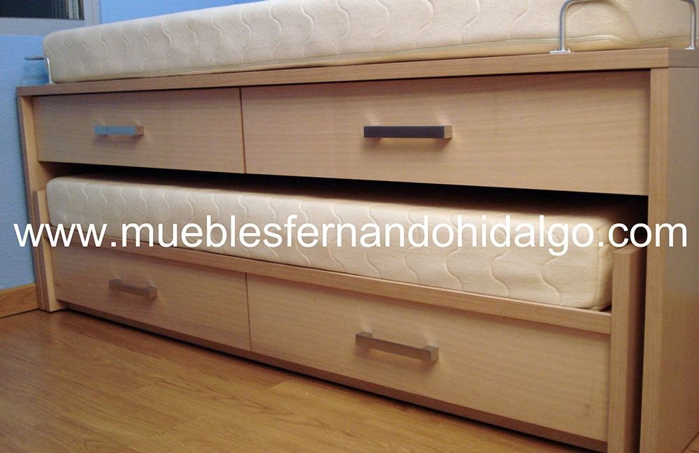 Una cama con dos cajones debajo y la web www.mueblesfernandohidalgo.com