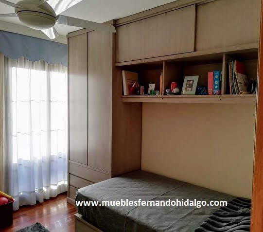 Un dormitorio con una cama individual y un ventilador de techo.