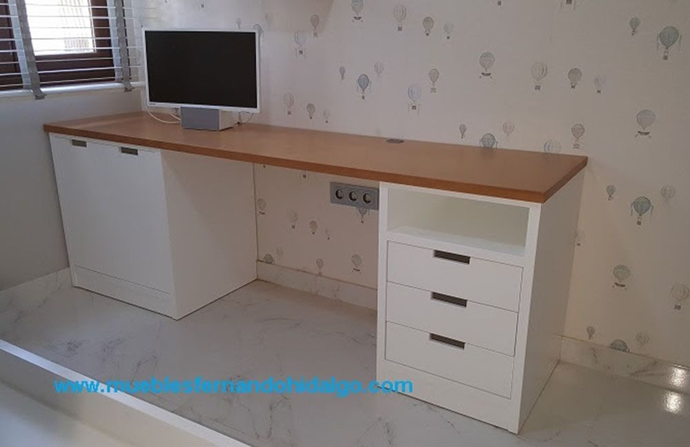 Un escritorio largo y blanco con cajones y una computadora encima.