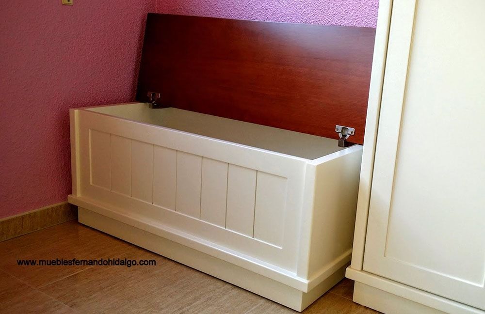 Un banco blanco con respaldo de madera se encuentra junto a una pared rosa.