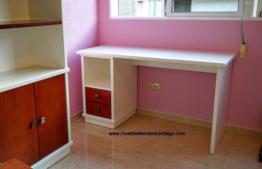 Un escritorio en una habitación con una pared rosa y la página web www.mueblesfernandochicago.com