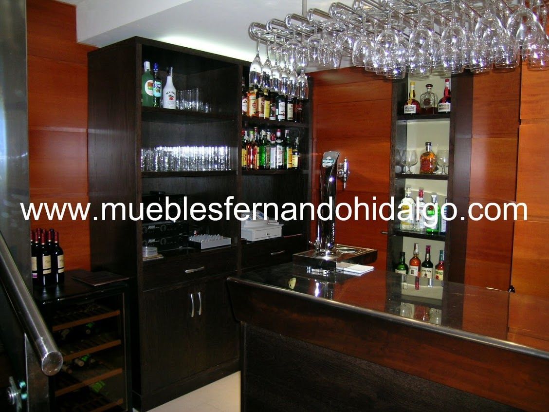 Una barra con botellas de vino y copas y la página web www.mueblesfernandohidalgo.com