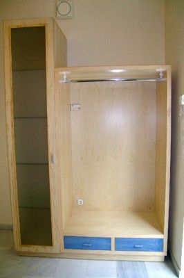 Un armario de madera con cajones azules y una puerta de cristal en una habitación.