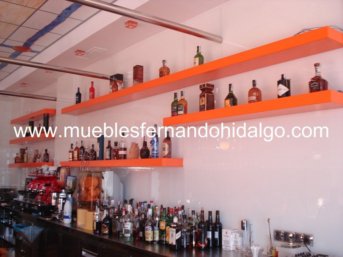 Un bar con muchas botellas en los estantes y la página web www.mueblesfernandohidalgo.com