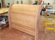 Un hombre sostiene un trozo de madera en un taller.