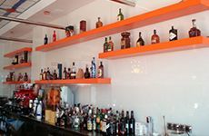 Un bar lleno de botellas de alcohol en estantes naranjas.