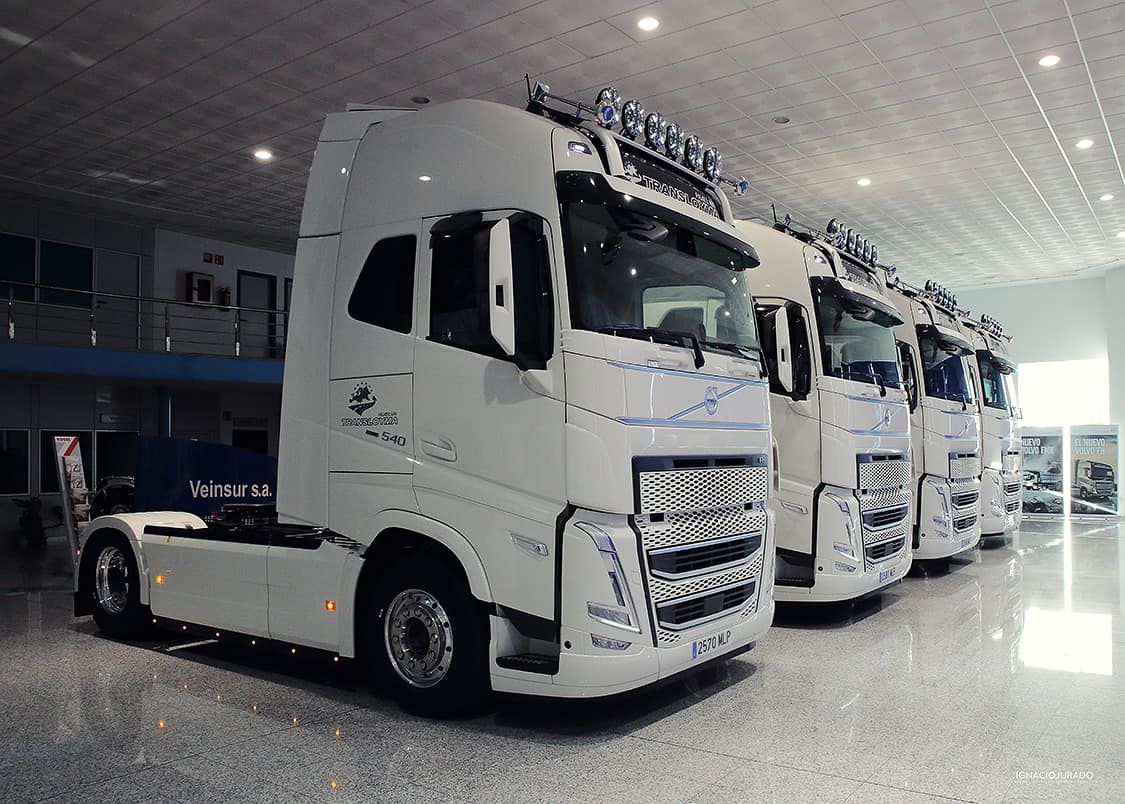 Repartidor cargando cajas en una camioneta blanca afuera de un almacén.