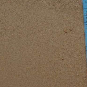 Un primer plano de un trozo de arena al lado de una regla.