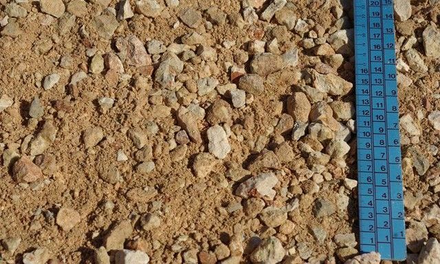 Una regla azul está sentada encima de una pila de grava.