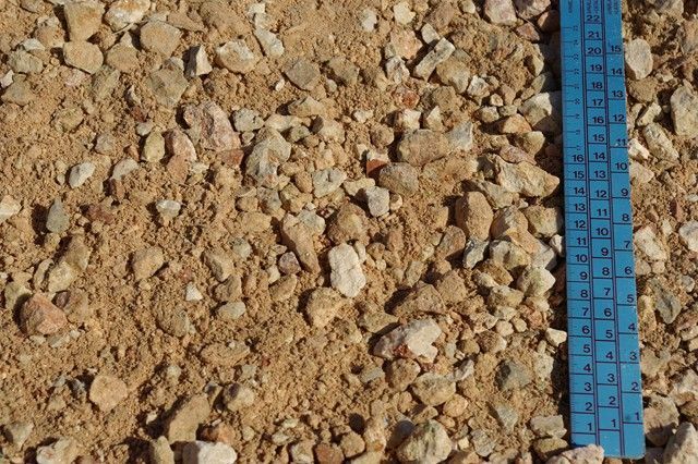 Una regla azul se encuentra sobre una pila de grava.