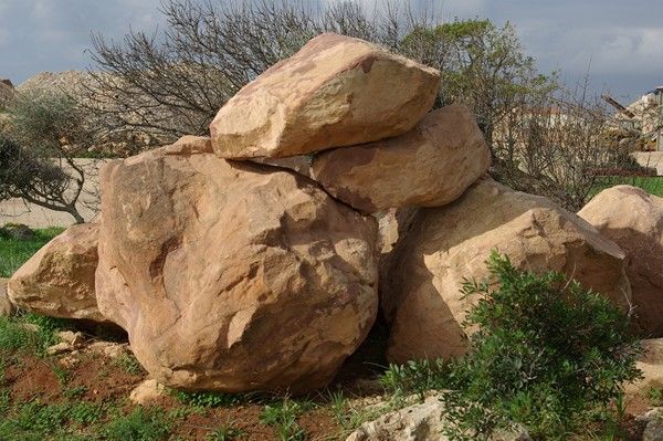 Un montón de rocas en un campo con árboles al fondo.