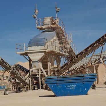 Un gran contenedor de basura azul se encuentra frente a una gran máquina.