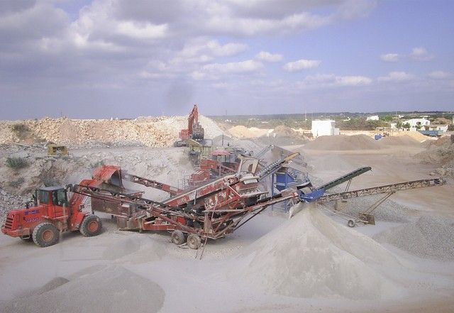 Se está cargando una gran pila de tierra en una cinta transportadora en una cantera.