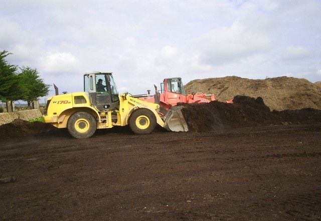Una excavadora amarilla empuja un montón de tierra al lado de una excavadora roja