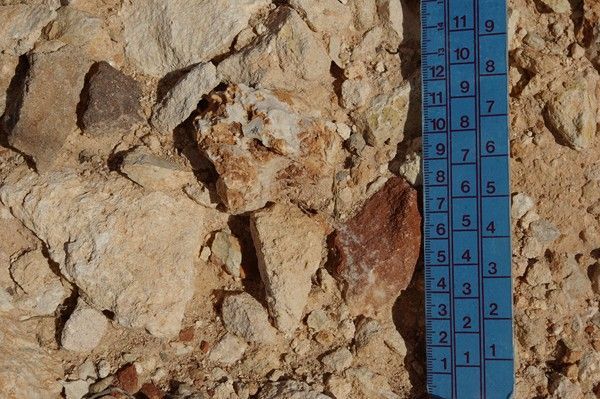 Una regla azul está sentada encima de una pila de rocas.