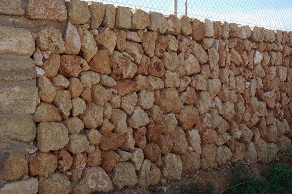 Un gran muro de piedra con el número 65 escrito en él.