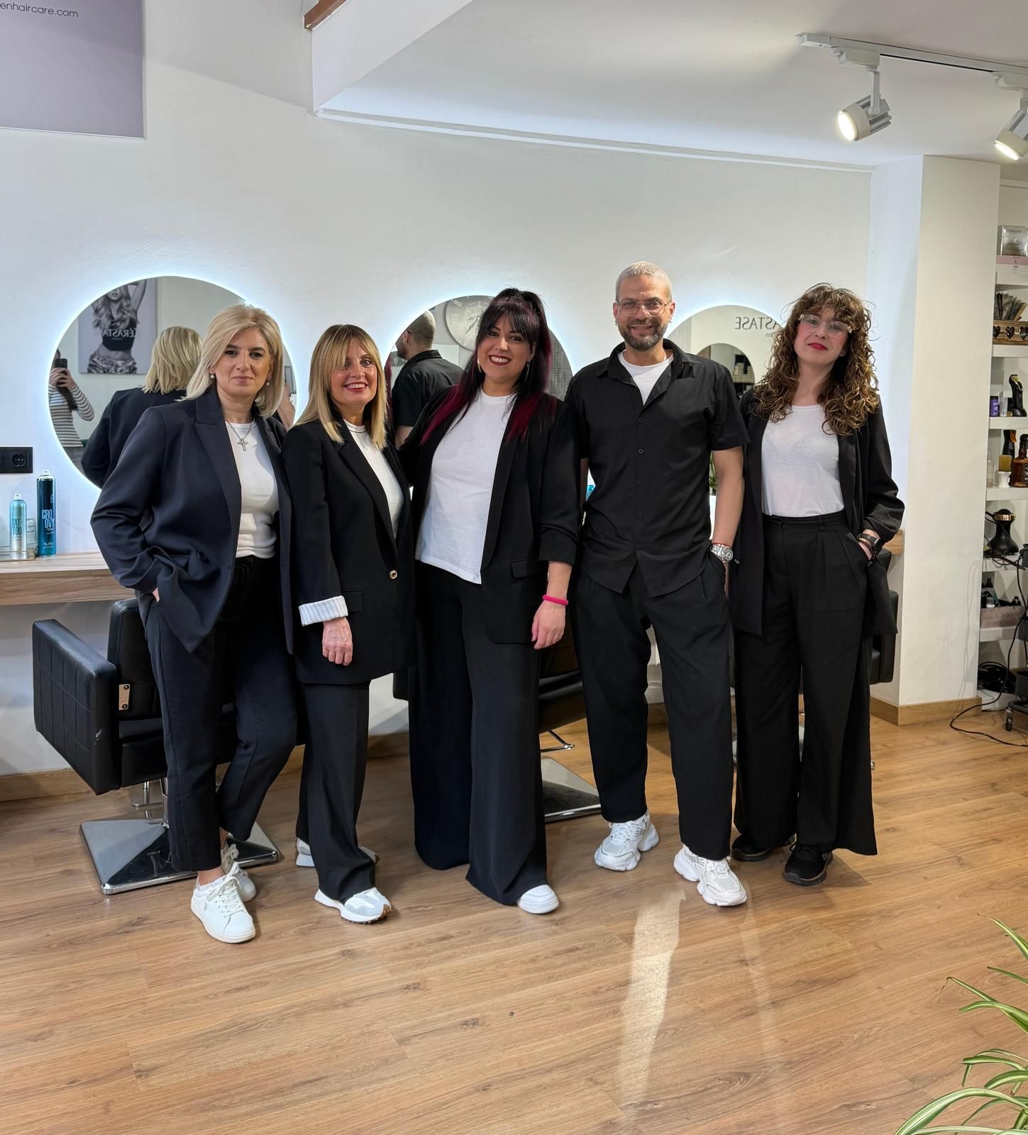 Interior de peluquería con espejos, sillas, plantas y una orquídea.