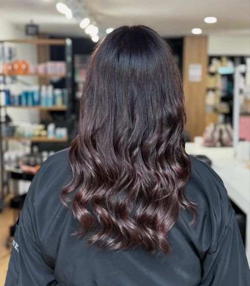 Vista posterior de una persona con cabello oscuro peinado en capas onduladas.
