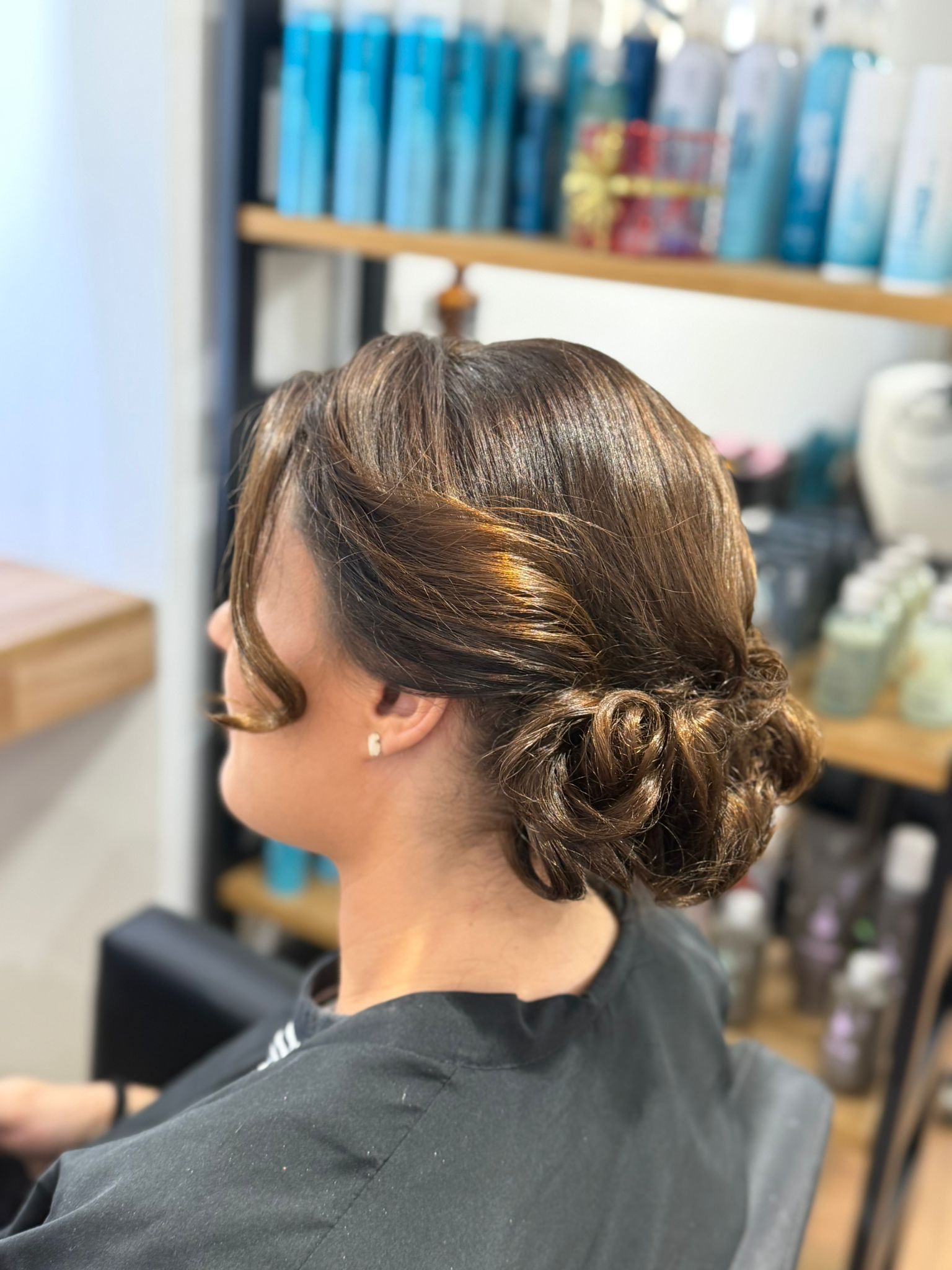 Mujer con cabello castaño recogido en una peluquería. 