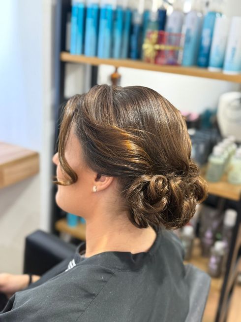 Mujer con cabello castaño recogido en una peluquería.