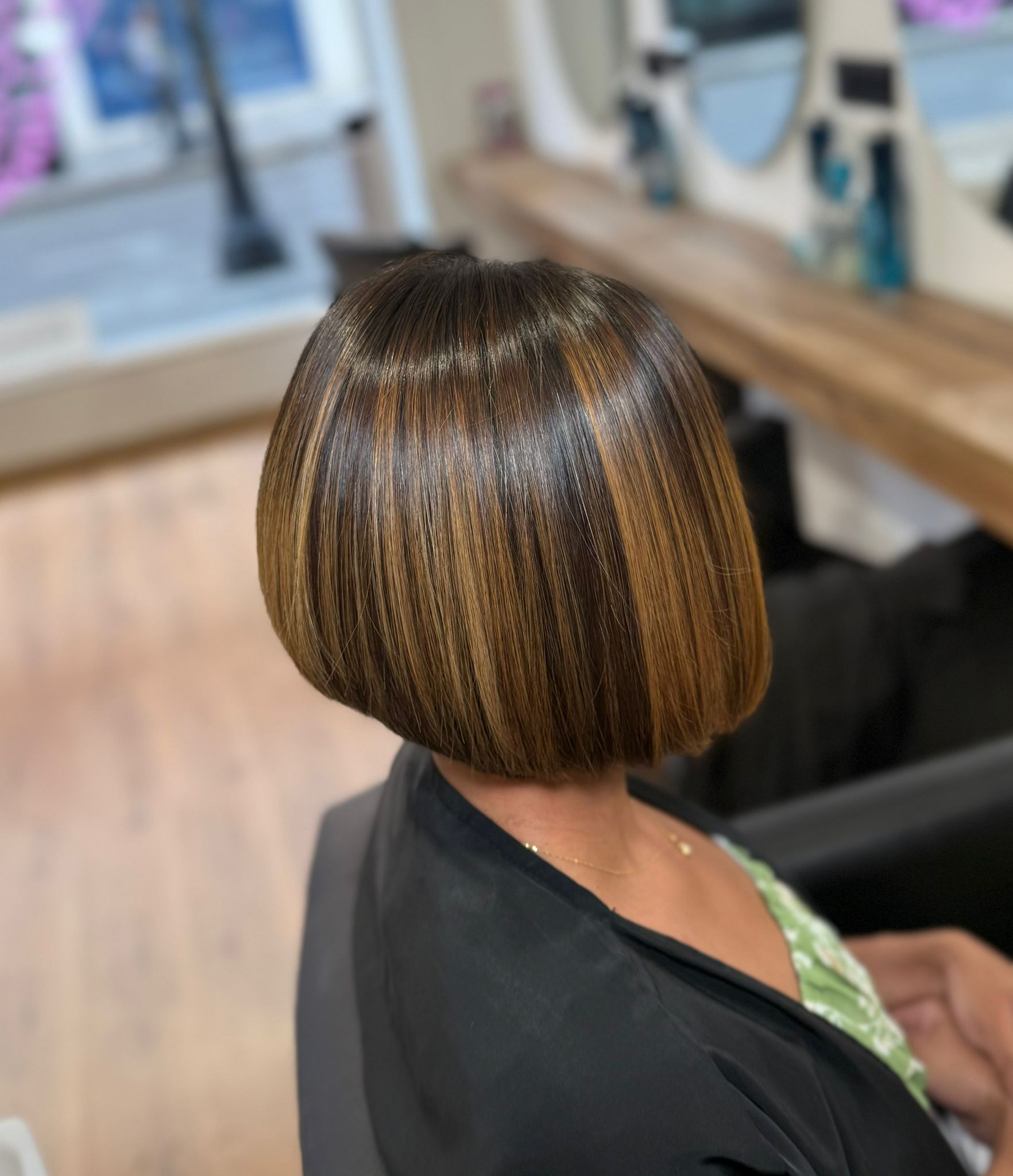 Mujer con peinado bob, reflejos castaños y rubios, en un entorno de salón.