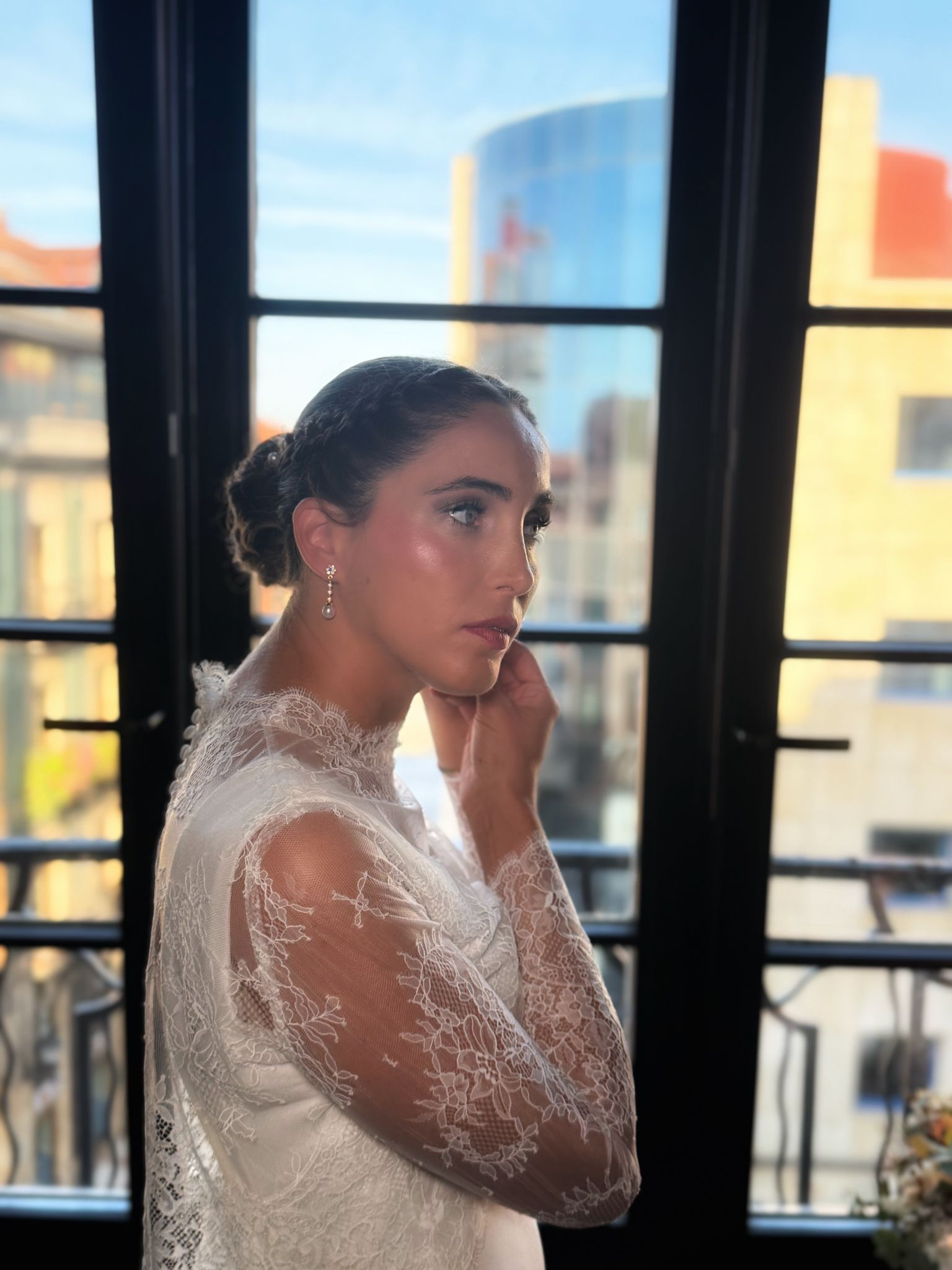 Mujer con mechas en una peluquería. Tiene los brazos levantados. Mechas rubias y castañas oscuras.