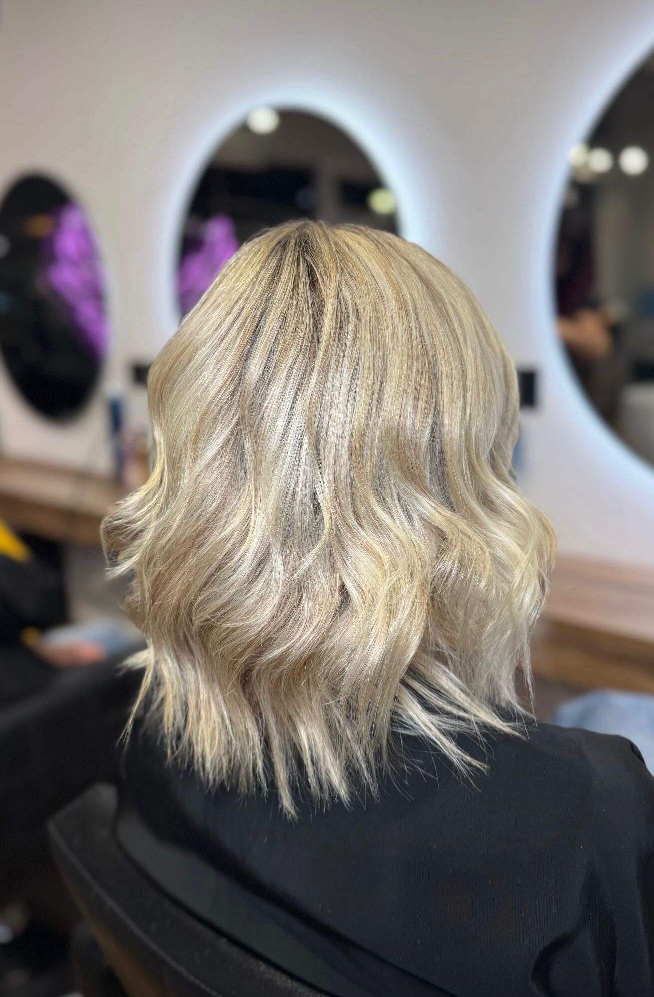 Corte de pelo bob rubio ondulado, vista desde atrás, en un salón.