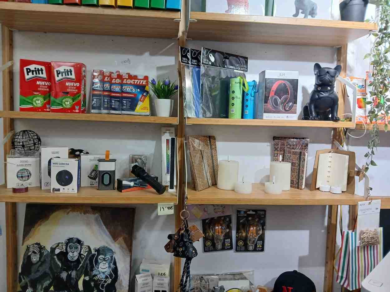 Estanterías repletas de artículos diversos, incluidos pegamento, papelería, productos electrónicos y objetos decorativos.