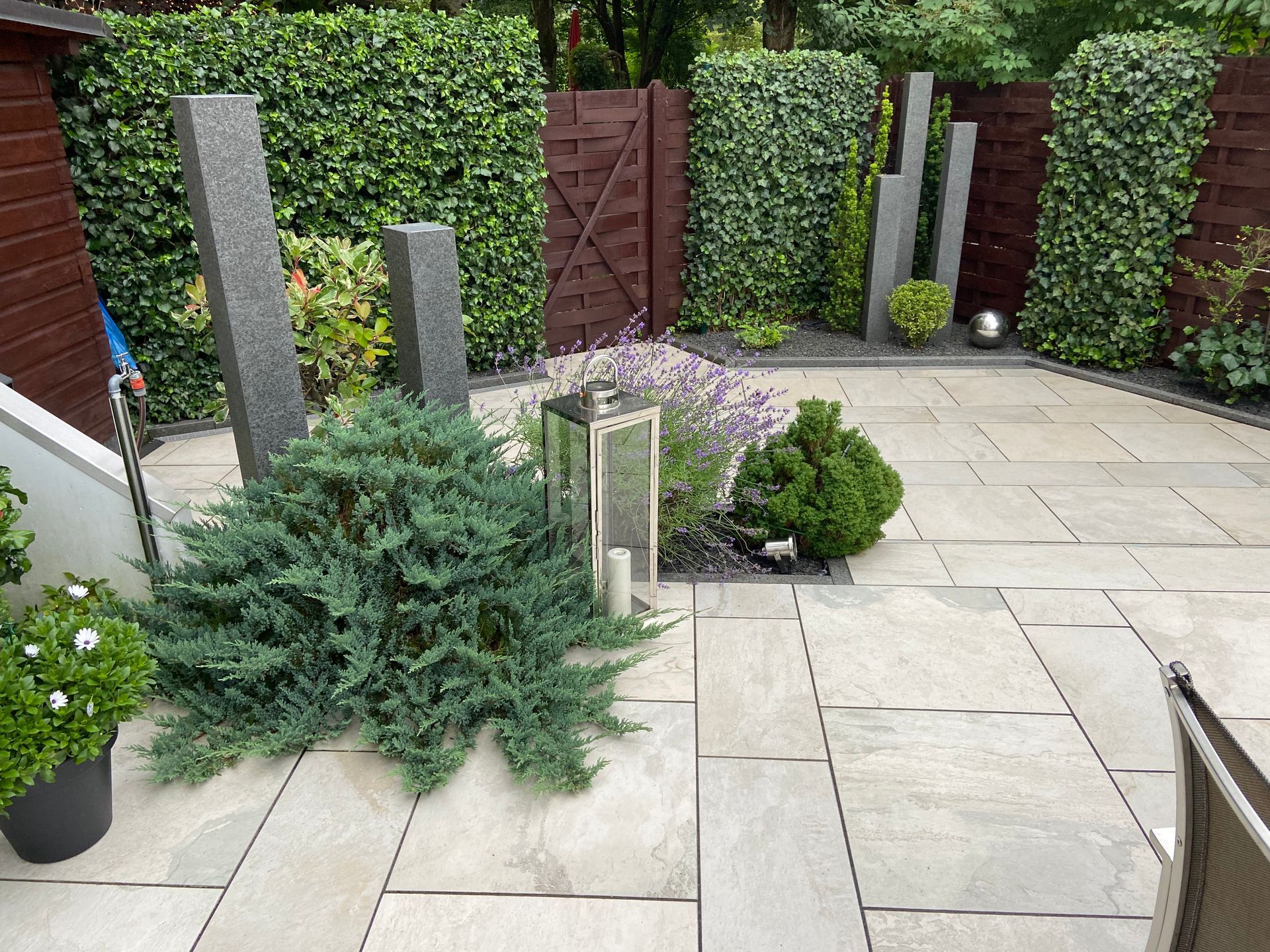 Ein üppiger Garten mit gewundenen Kieswegen, farbenprächtigen Blumen und vielfältigen Bäumen unter einem bewölkten Himmel.