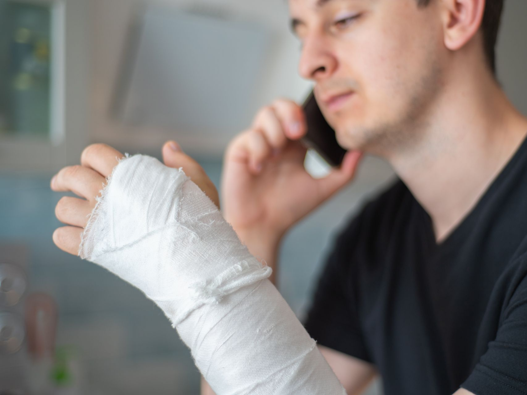 Un homme avec un plâtre au bras parle au téléphone.