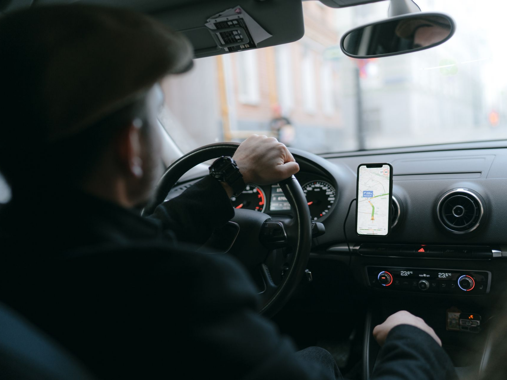 Personne au volant, utilisant son téléphone avec une application de navigation.