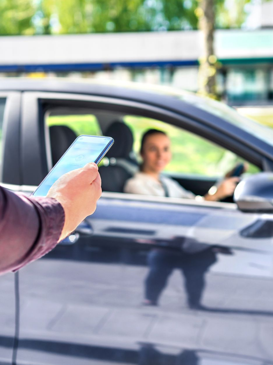 Personne tenant un téléphone, passager d'une voiture visible.