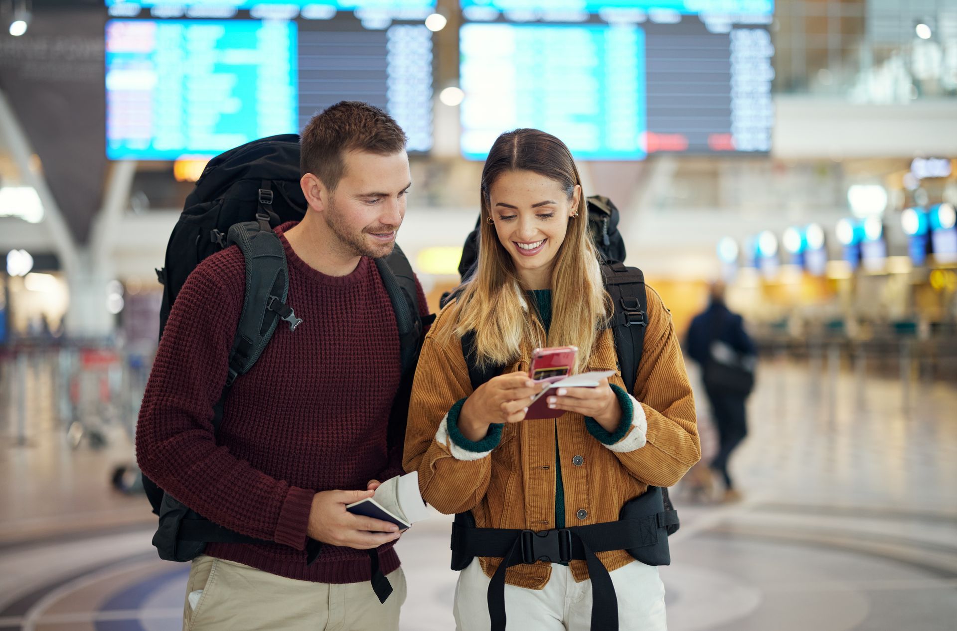 Un couple avec des sacs à dos à l'aéroport, regardant un passeport.